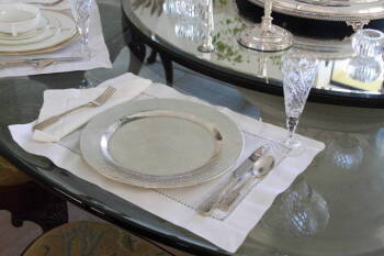 SET OF HAMMERED METAL CHARGERS, WHITE LINEN TABLE WARE, AND FIVE WINE GLASSES.