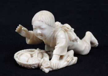 A VINTAGE FIGURAL JAPANESE NETSUKE OF A BOY WITH F