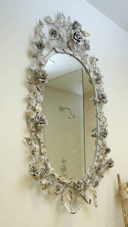 AN OVAL GILDED TOLEWARE FLORAL WALL MIRROR